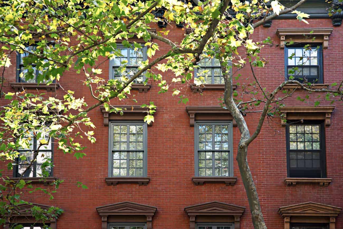 A red brick building with a tree in front of it.