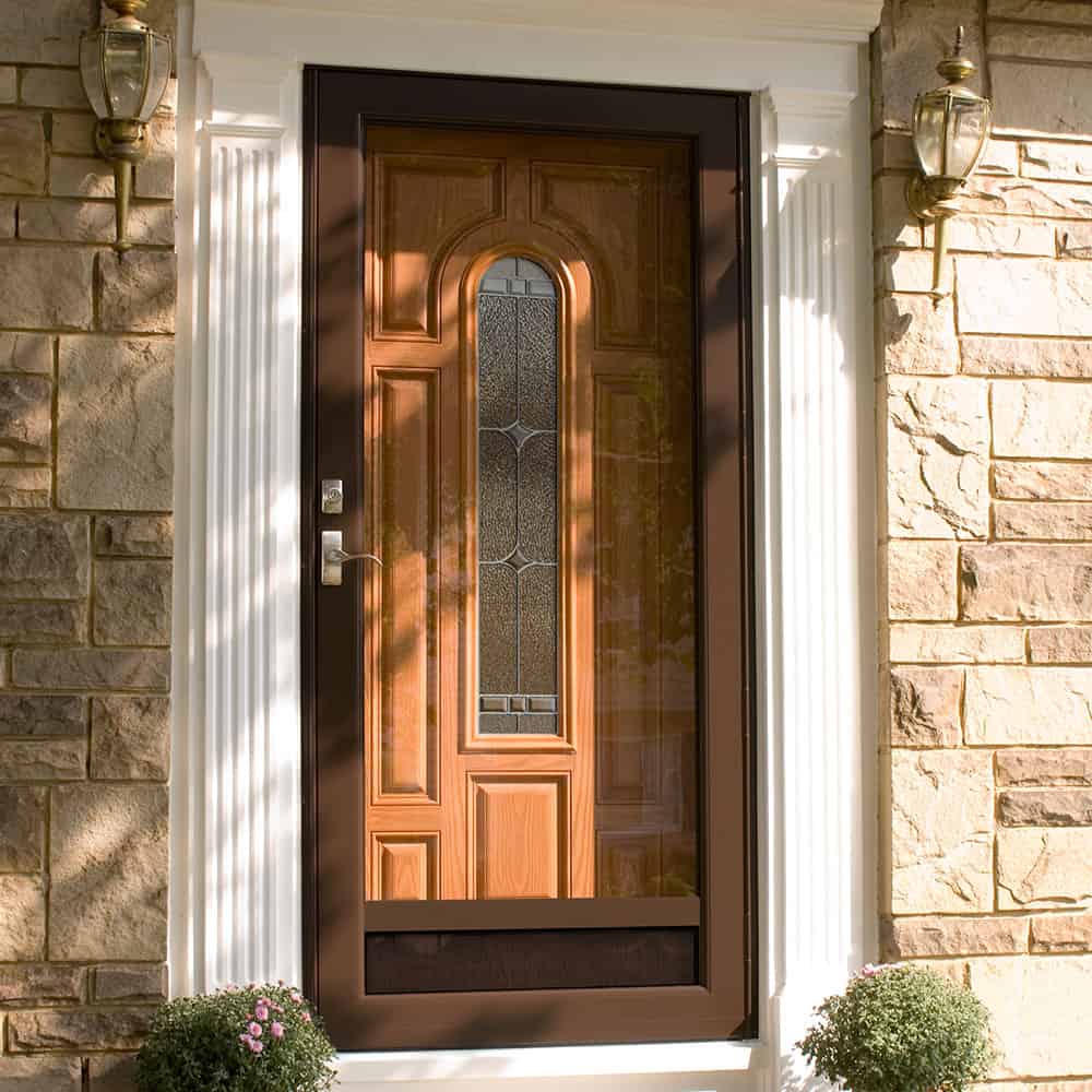 Brown front door with decorative glass in center, in stone-front home.