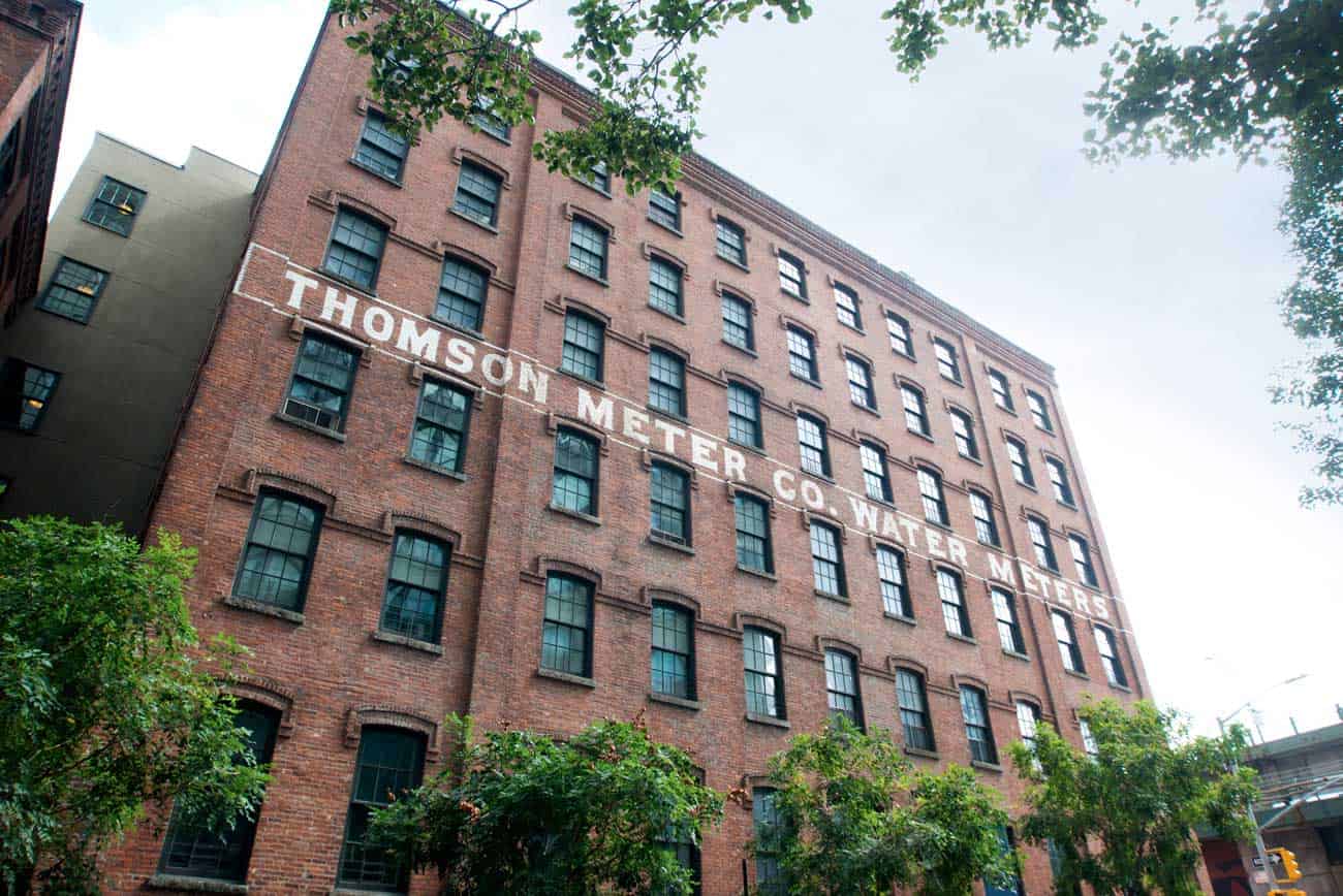 A red brick building with Thomson Meter Co. Water Meters painted in white.