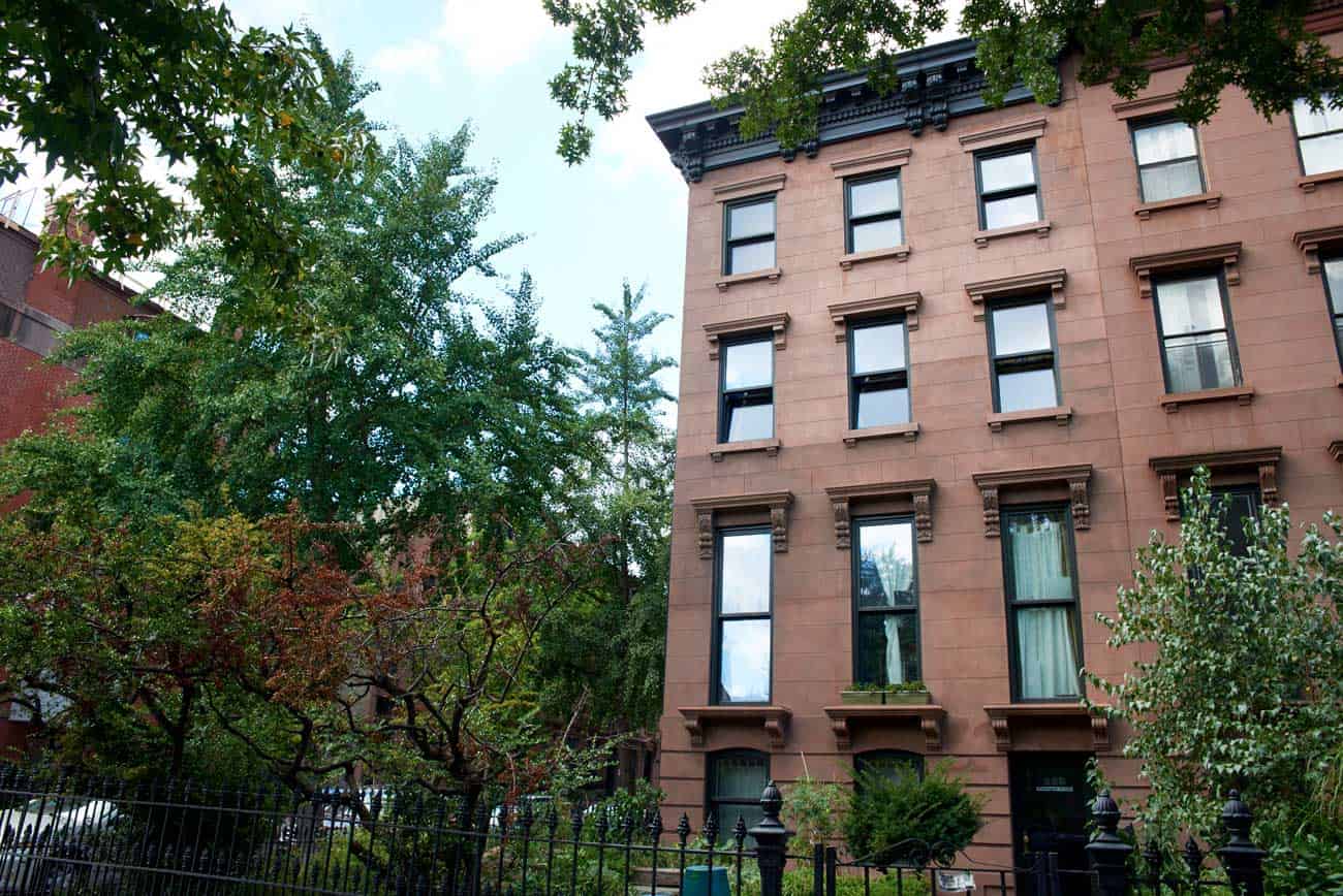 A brownstone building with a fence in front of it.
