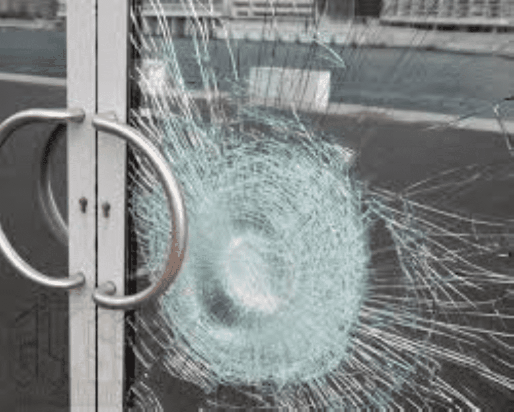 A shattered safety glass door with semi-circular pulls on it.