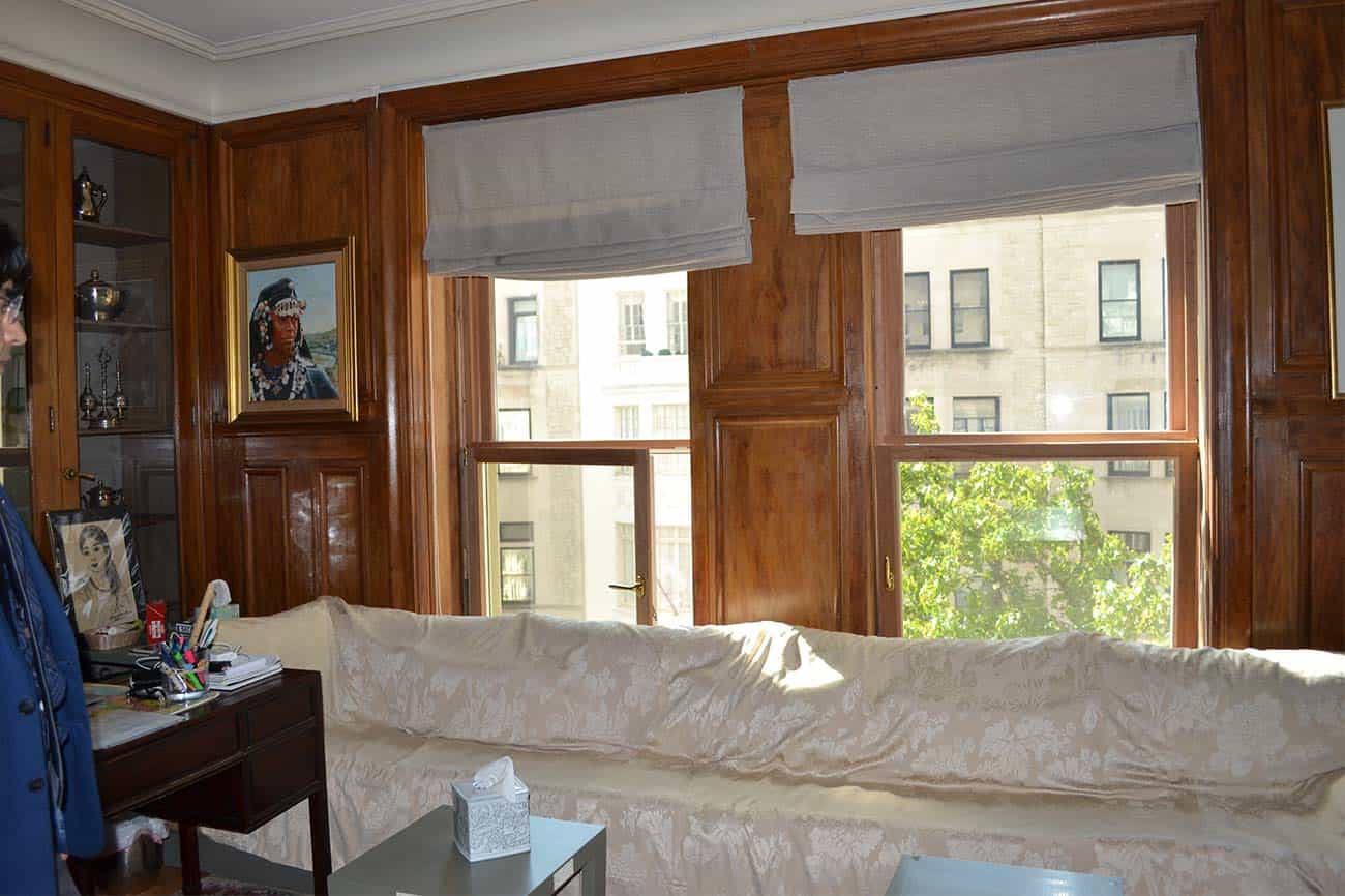 A covered-up couch in front of two windows.