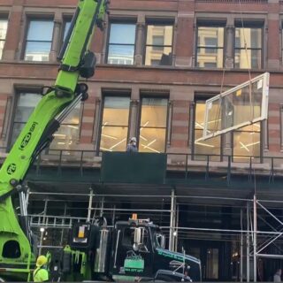 This is an image of a window being hoisted up to the second floor of a building.