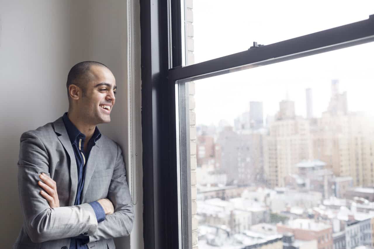 a man leaning against a window looking out through a window screen