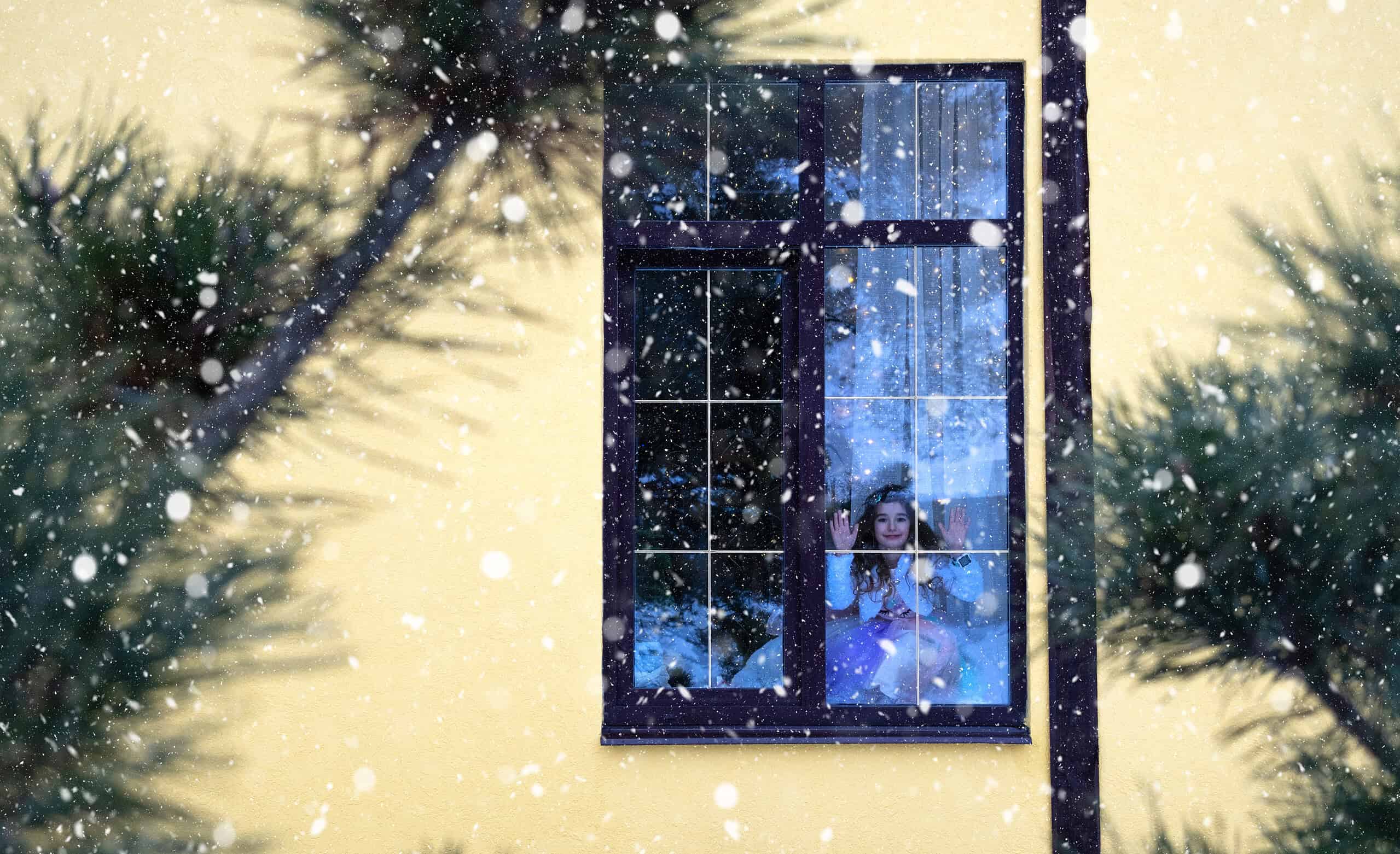 wintered home is cozy as Girl looks out window at snow